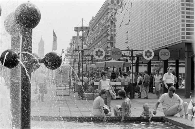 Passers-by at the Kugelbrunnen on Karl-Marx-Strasse ( Breiter Weg ) in front of the solemnly decorated children's department stores' on the occasion of the 21st Workers' Festival in Magdeburg in the federal state of Saxony-Anhalt in the territory of the former GDR, German Democratic Republic