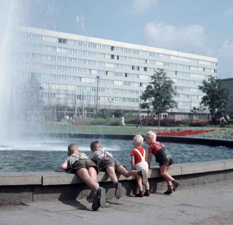 Kinder spielen an einem Springbrunnen am Ulrichplatz im Zentrum von Magdeburg. Die Magdeburger Innenstadt war während des Zweiten Weltkrieges zum großen Teil zerstört worden. Die meisten beschädigten Gebäude wurden in der DDR abgerissen und durch Plattenbauten ersetzt, hier das Bürogebäude der s.g. 'Blaue Bock' im Hintergrund.