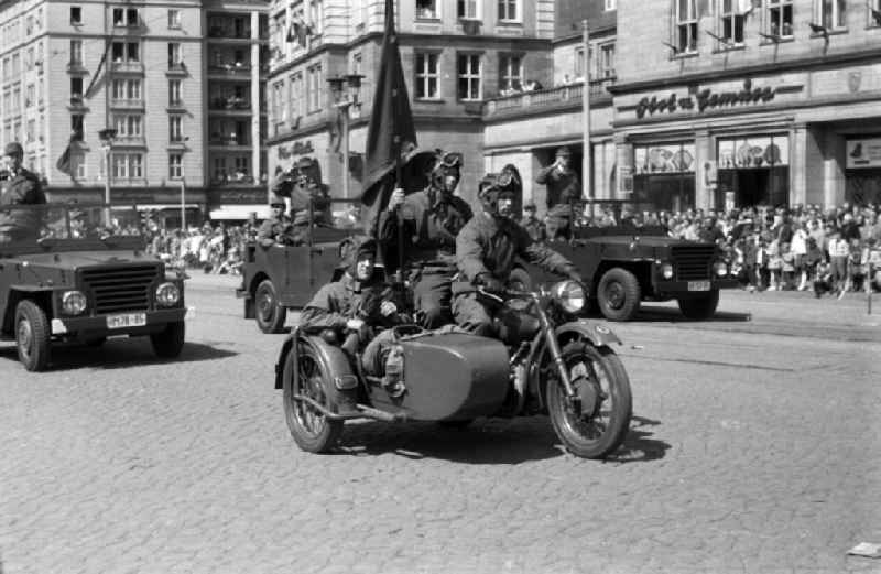 Uniformed and motorized units of the combat groups of the GDR at the parade on May 1 in Magdeburg. Here when passing with a military salute. In the foreground members of the Battle Group on a motorcycle with a sidecar and troop flag