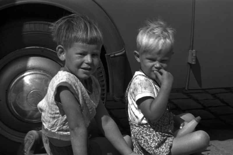 Two little boys sitting on the sidewalk in front of a VW Beetle in Magdeburg in Saxony - Anhalt