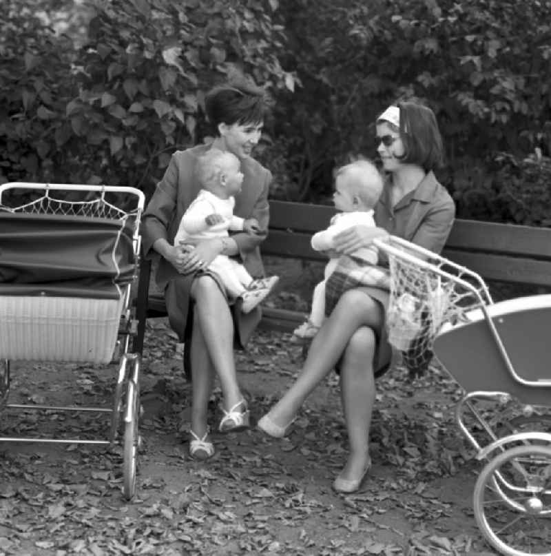 Two mothers with their babies sitting on a park bench in Magdeburg
