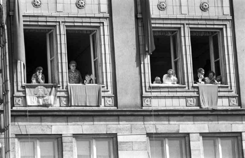 People look out the window of her apartment in Magdeburg. The facade of residential house was decorated with flags on the occasion of May 1st