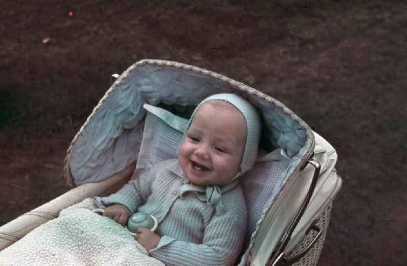 Baby sitzt im Kinderwagen und lacht. Baby is sitting in a pram / buggy and laughs.