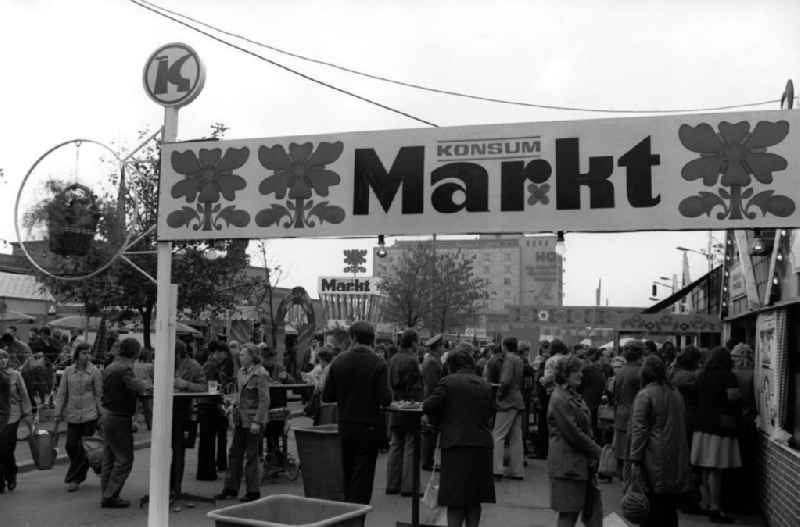 Blick auf den gut besuchten Konsum Markt in Merseburg. Transparent / Werbebanner mit der Aufschrift 'Konsum Markt'. Passanten stehen an Tischen und Buden beim Essen und Trinken.