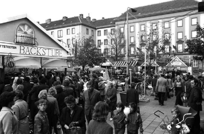 Blick auf den gut besuchten Konsum Markt in Merseburg. Passanten stehen am Stand einer Backstub (l), rechts steht ein Kind neben einem Kinderwagen.