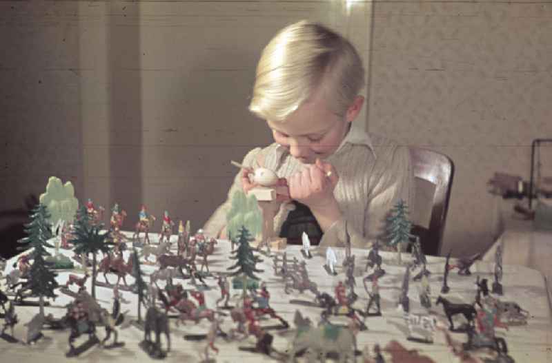 Weihnachten in der Nachkriegszeit. Ein Junge spielt mit Spielfiguren an Heiligabend. Christmas in the postwar period. A boy plays with meeples at the Christmas Eve.