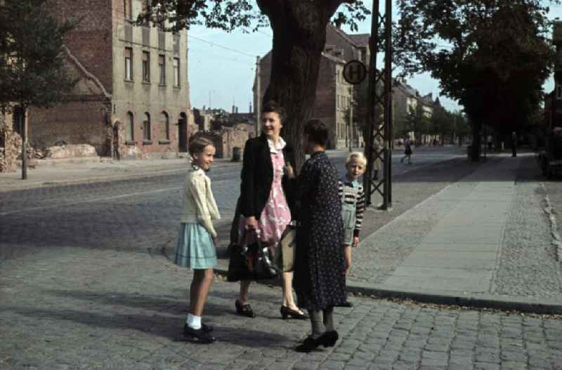 Frauen und Kinder auf der Straße im Gespräch. Trümmer im Hintergrund. Women and children in a conversation on the street. Debris in the background.