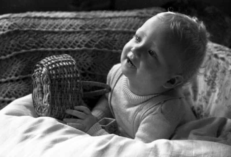 A small laughing boy sits in his little bed in Merseburg in the federal state Saxony-Anhalt in Germany
