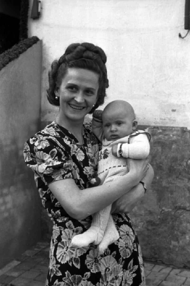 A woman holds a baby on the arm in Merseburg in the federal state Saxony-Anhalt in the area of the former GDR, German democratic republic