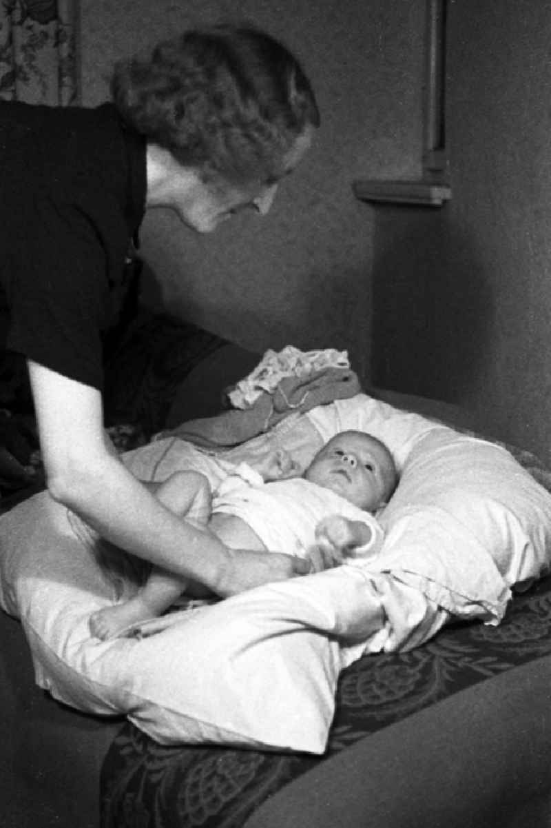 A mother wraps her child on a pillow in Merseburg in the federal state Saxony-Anhalt in the area of the former GDR, German democratic republic