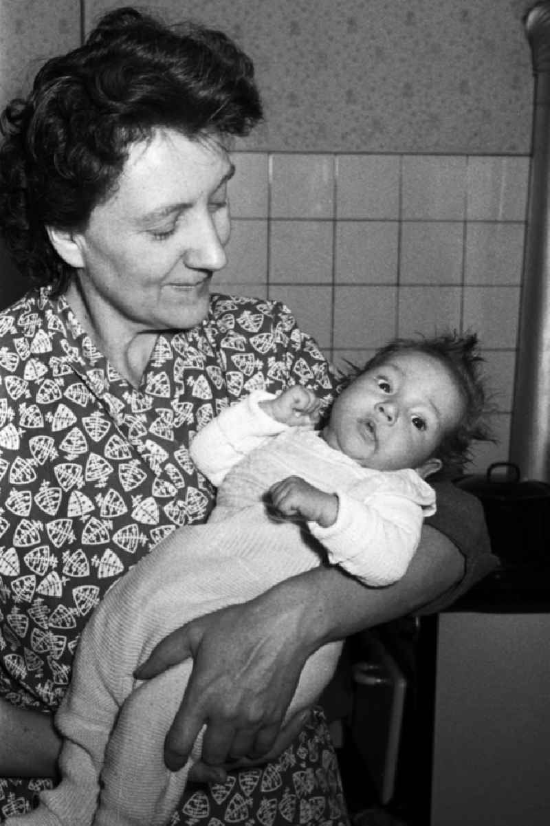 A woman holds a baby on the arm in Merseburg in the federal state Saxony-Anhalt in the area of the former GDR, German democratic republic