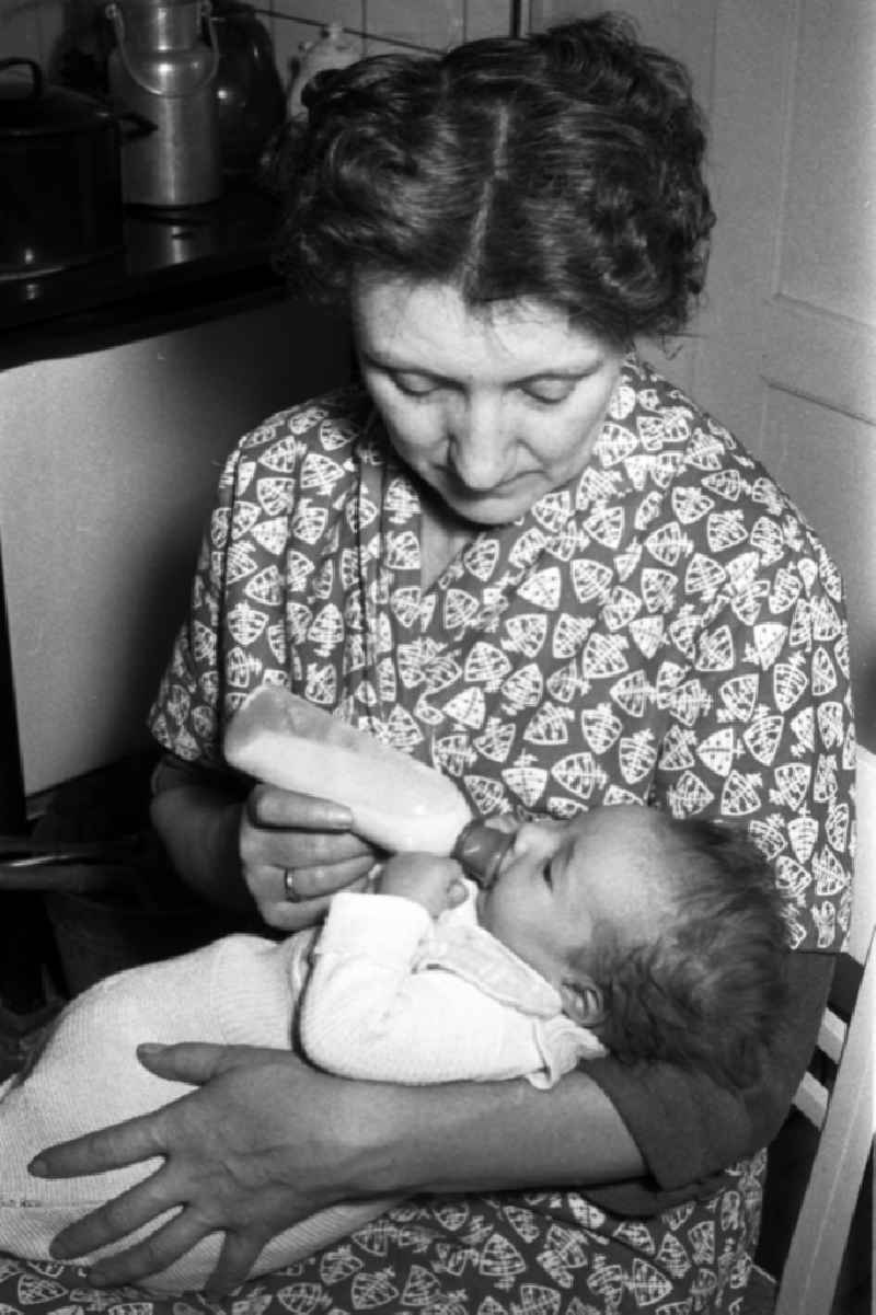 A mother gives to her baby the teat bottle in Merseburg in the federal state Saxony-Anhalt in the area of the former GDR, German democratic republic