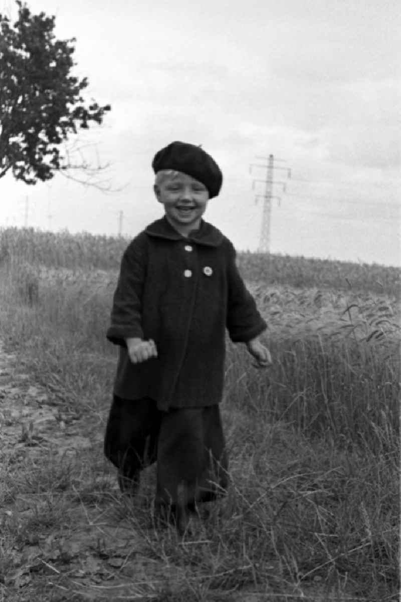 A small child in baggy trousers and with beret runs on a country lane in Merseburg in the federal state Saxony-Anhalt in the area of the former GDR, German democratic republic
