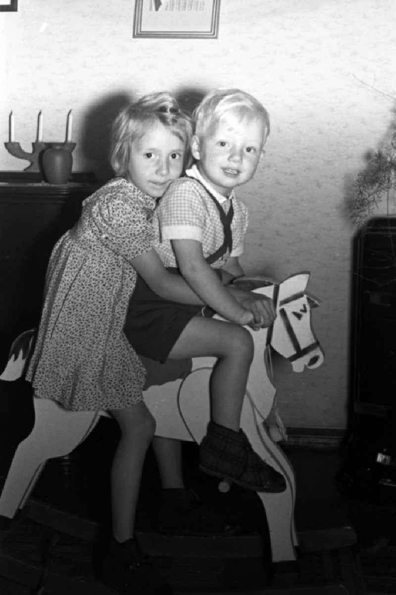 Two children sit on a rocking horse of wood in Merseburg in the federal state Saxony-Anhalt in Germany