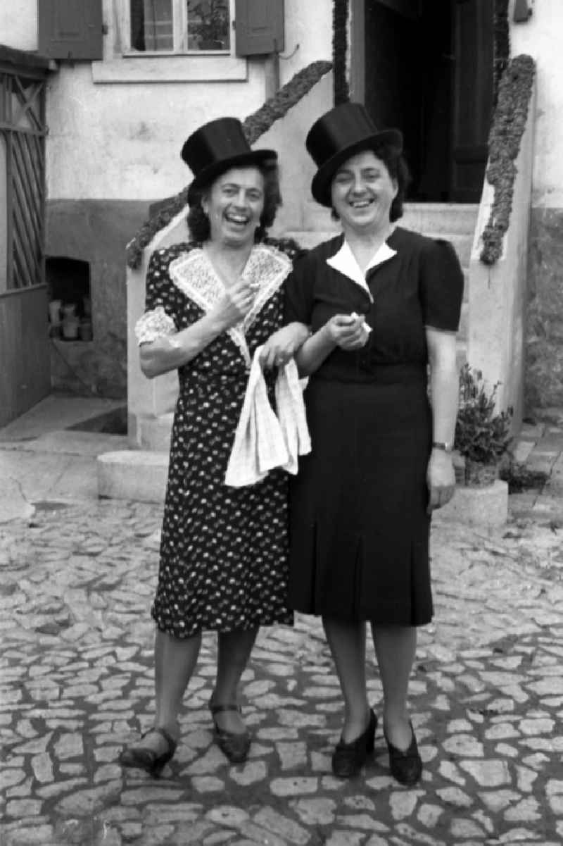 Two laughing women with cylinders on the head in Merseburg in the federal state Saxony-Anhalt in Germany