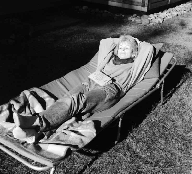 A young woman lying on a camp bed and basks in Mittenwalde in Brandenburg on the territory of the former GDR, German Democratic Republic
