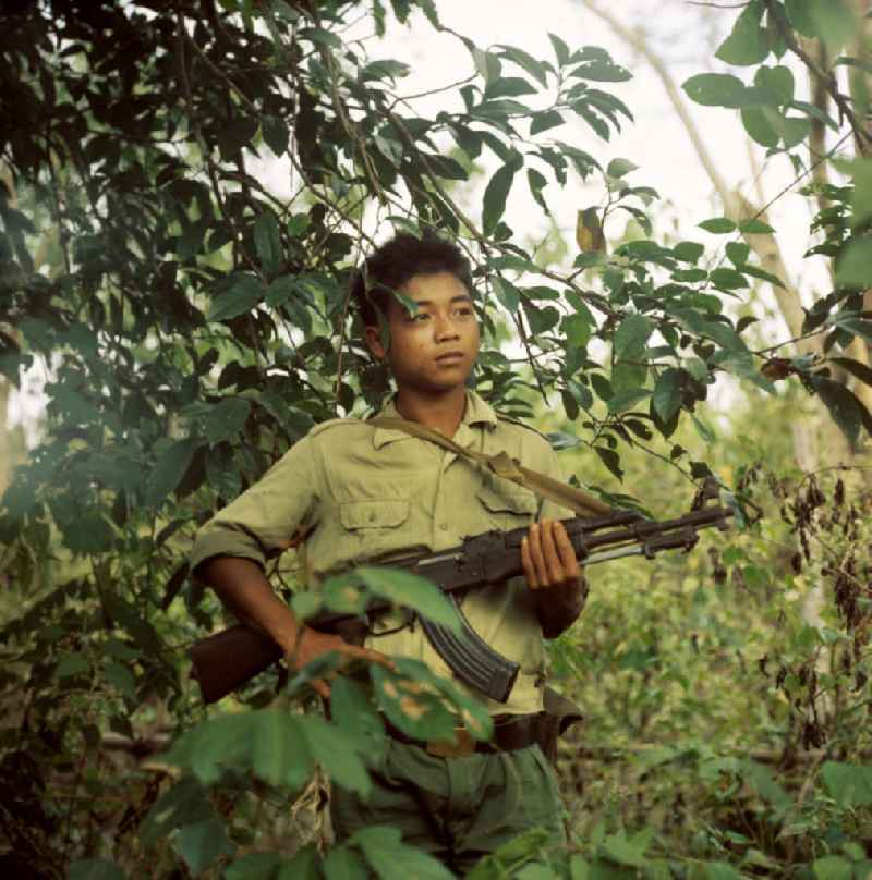 Junger Soldat der laotischen Armee in der Demokratischen Volksrepublik Laos. Erst ein Jahr zuvor, am 2. Dezember 1975, war durch die kommunistisch geprägten Kräfte die Volksrepublik Laos ausgerufen worden. Die politische und wirtschaftliche Situation blieb aber auch in den Folgejahren unsicher und instabil. Immer wieder kam es zu Rebellionen aus dem Hinterland, die mit Hilfe der Armee und ausländischer, v.a. vietnamesischer, Unterstützung gewaltsam niedergeschlagen wurden.