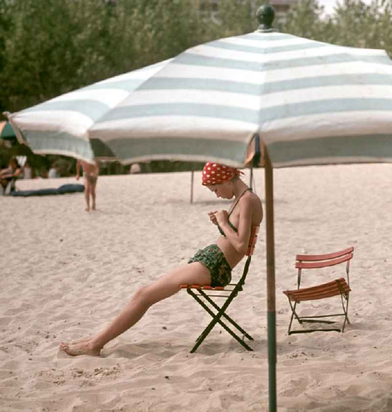 Eine junge Frau sitzt auf einem Stuhl am Strand von Nessebar am Schwarzen Meer in der Volksrepublik Bulgarien. Reisen in das Ausland war den DDR-Bürgern nur in die befreundeten sozialistischen Länder erlaubt, für Bulgarien erfolgte in der Regel die Erteilung einer Reisegenehmigung.