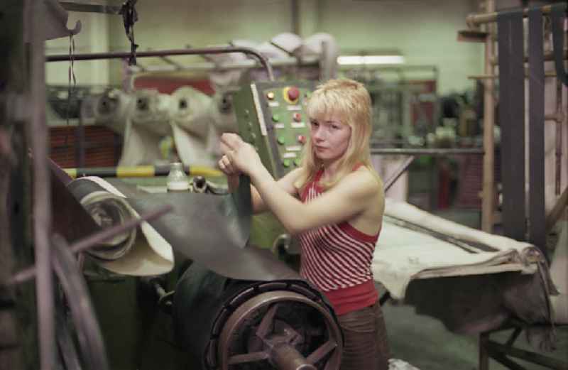 Young woman as a worker at work and factory equipment for tire production in the VEB tire factory on Ihlenfelder Strasse in Neubrandenburg, of Mecklenburg-Western Pomerania on the territory of the former GDR, German democratic republic