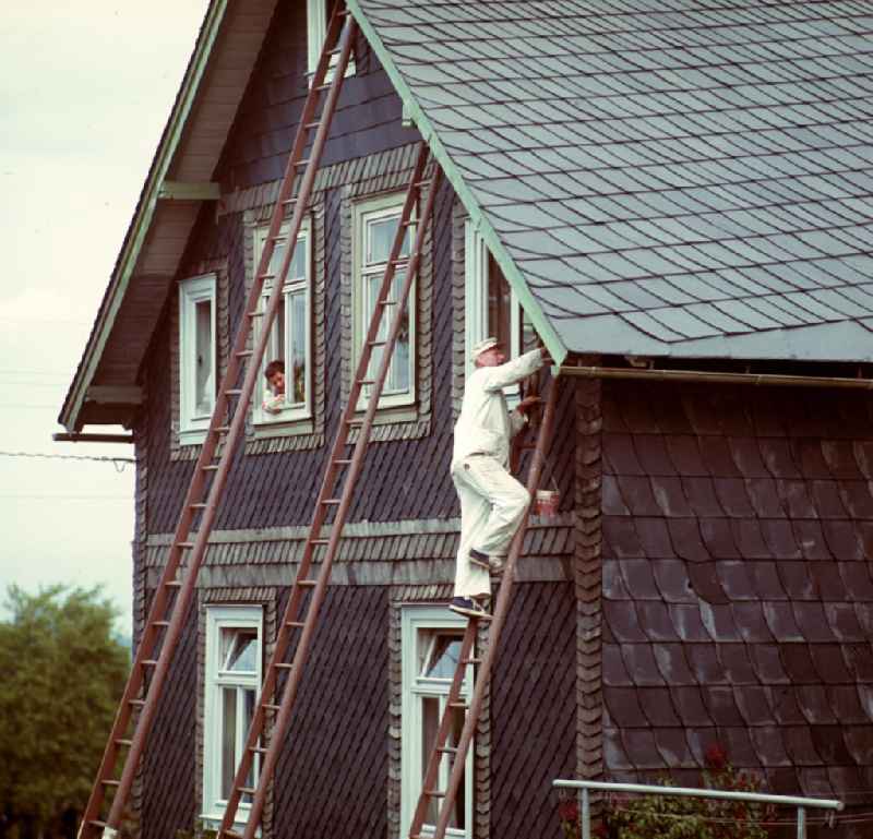 Malerarbeiten an einem mit Schiefer bedeckten Haus in Neuhaus im Thüringer Wald. Der Thüringer Wald mit seinen Wander- und Erholungsmöglichkeiten war ein beliebtes Urlaubsziel in der DDR.