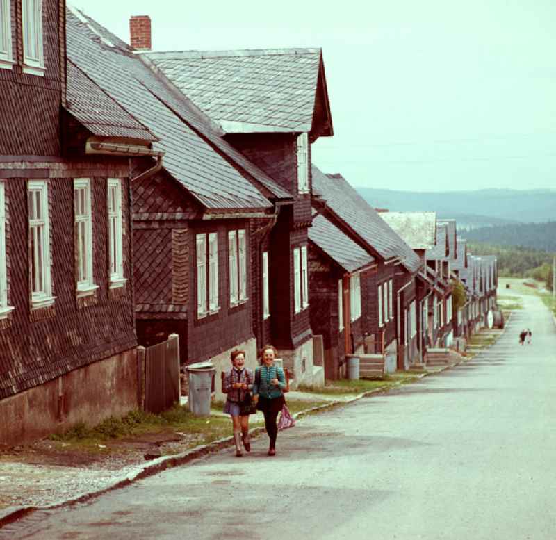 Zwei Mädchen mit Ranzen und Sportbeutel auf dem Weg zur Schule in Neuhaus im Thüringer Wald. Die Fassaden und Dächer der Häuser des Ortes sind mit Schiefer bedeckt. Der Thüringer Wald mit seinen Wander- und Erholungsmöglichkeiten war ein beliebtes Urlaubsziel in der DDR.
