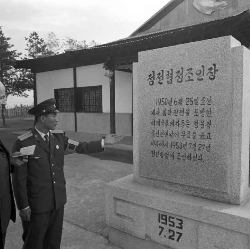 Angehörige der nordkoreanischen Armee zeigen einem Besucher in Panmunjeom (auch Joint Security Area JSA genannt) einen Gedenkstein zur Erinnerung an den Koreakrieg und das Waffenstillstandsabkommen von 27.7.1953. Panmunjeom ist eine militärische Siedlung in der entmilitarisierten Zone zwischen Nord- und Südkorea und seit dem Waffenstillstandsabkommen 1953 das Hauptquartier der Military Armistice Commission (MAC), die die Einhaltung des Waffenstillstands überwacht. Die militärische Demarkationslinie (MDL) verläuft in der Mitte der abgebildeten Hütte. Seit den Gesprächen des Waffenstillstandskomitees des Roten Kreuzes im Herbst 1971 wurden in Panmunjeom Gespräche zwischen Nord- und Südkorea geführt, wobei vor allem das Thema der Familienzusammenführungen bzw. -treffen im Mittelpunkt stand. Es ist die einzige zollähnliche 'offene' Grenzstelle, wo ohne Grenzübertretung am selben Tisch Verhandlungen und Gespräche stattfinden konnten.