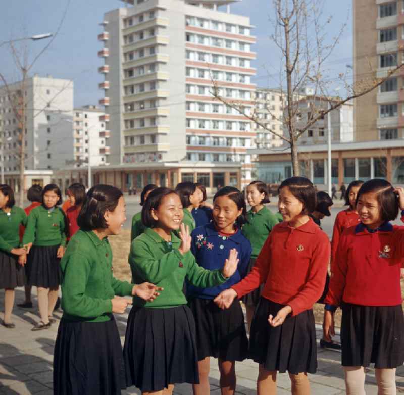 Schulmädchen auf einer Straße in Pjöngjang, der Hauptstadt der Koreanischen Demokratischen Volksrepublik (KDVR). Im Hintergrund Plattenbauten im sozialistischen Stil. Die nordkoreanische Hauptstadt war nach der Zerstörung im Koreakrieg vor allem mit Unterstützung der Sowjetunion in den 50er und 6