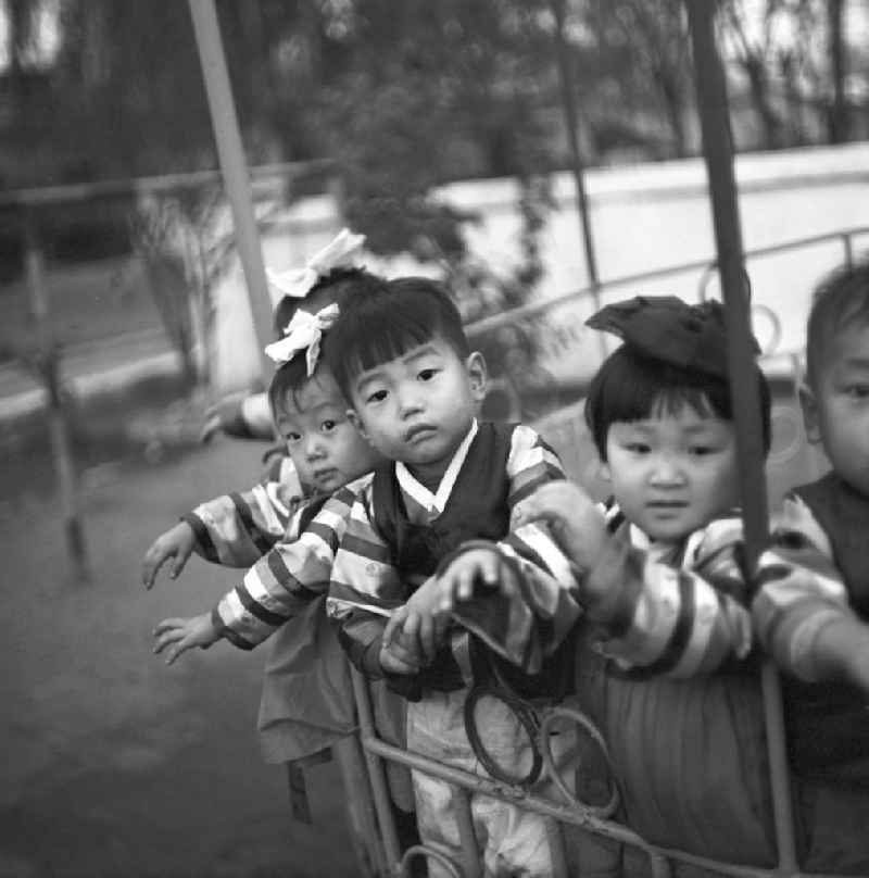 Kinder stehen in einem Karussell auf dem Spielplatz in einem Kindergarten in Pjöngjang, der Hauptstadt der Koreanischen Demokratischen Volksrepublik KDVR - Nordkorea / Democratic People's Republic of Korea DPRK - North Korea.