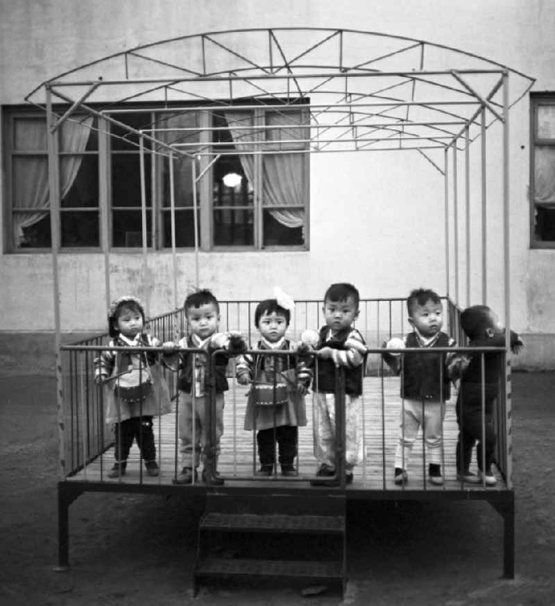 Kinder stehen in einer Art 'Laufstall' auf dem Spielplatz in einem Kindergarten in Pjöngjang, der Hauptstadt der Koreanischen Demokratischen Volksrepublik KDVR - Nordkorea / Democratic People's Republic of Korea DPRK - North Korea.