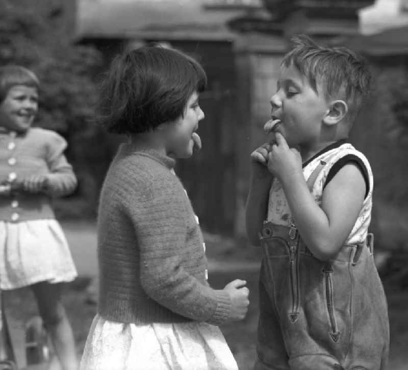 Zeig mal Deine Zunge - Kinder spielen auf einer Straße in dem kleinen Dorf Pomßen in der Nähe von Leipzig und strecken sich gegenseitig die Zunge raus.