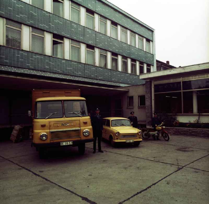 Blick in den Innenhof der Postfiliale in Potsdam Babelsberg, Karl-Liebknecht-Straße 138. Drei Postangestellte neben einem LKW vom Typ Robur, einem Trabant und einem Leichtkraftrad der Marke Simson Sperber (Typbezeichnung SR4-3).