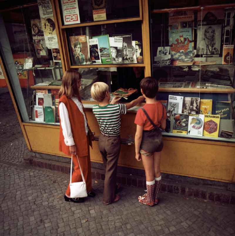 Kinder kaufen ein Magazin an einem Zeitungskiosk in Potsdam. In der Auslage verschiedene Zeitschriften, Magazine und Illustrierte.