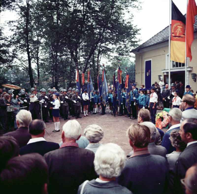 Pioniere und NVA Soldaten gedenken zum Todestag von Ernst Thälmann. Pioniere mit Halstuch stehen neben Kränzen und Flagge der DDR vor Gedenktafel mit der Aufschrift 'Wir wollen treu, fest, stark und siegesbewußt im Handeln sein wie Ernst Thälmann'.