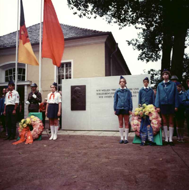Pioniere und NVA Soldaten gedenken zum Todestag von Ernst Thälmann. Pioniere mit Halstuch stehen neben Kränzen und Flagge der DDR vor Gedenktafel mit der Aufschrift 'Wir wollen treu, fest, stark und siegesbewußt im Handeln sein wie Ernst Thälmann'