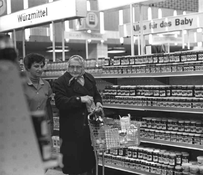 Kundin und Verkäuferin vor einem Regal mit Brotaufstrichen / Würzmittel  in der HO Kaufhalle im Ortsteil Lütten Klein in Rostock. Eröffnung am 04.