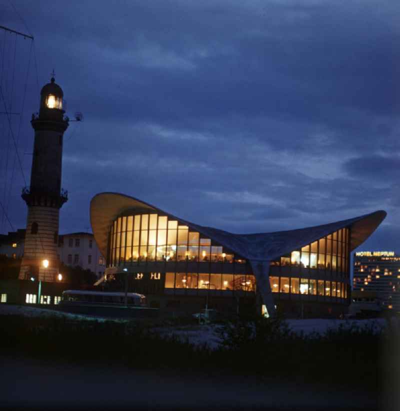 Blick auf die Wahrzeichen von Warnemünde bei Nacht - der Leuchtturm, der sogenannte 'Teepott' und im Hintergrund das Hotel Neptun. Der 36,9