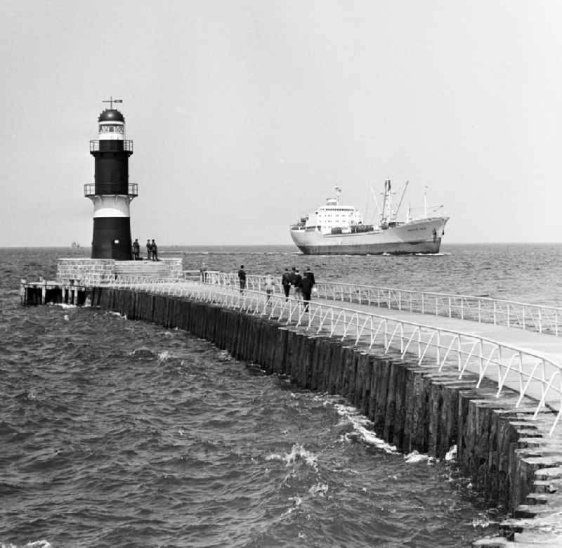 The cargo ship 'Krasnoye Selo' moves in Warnemuende at the pier and the lighthouse passing towards the port of Rostock