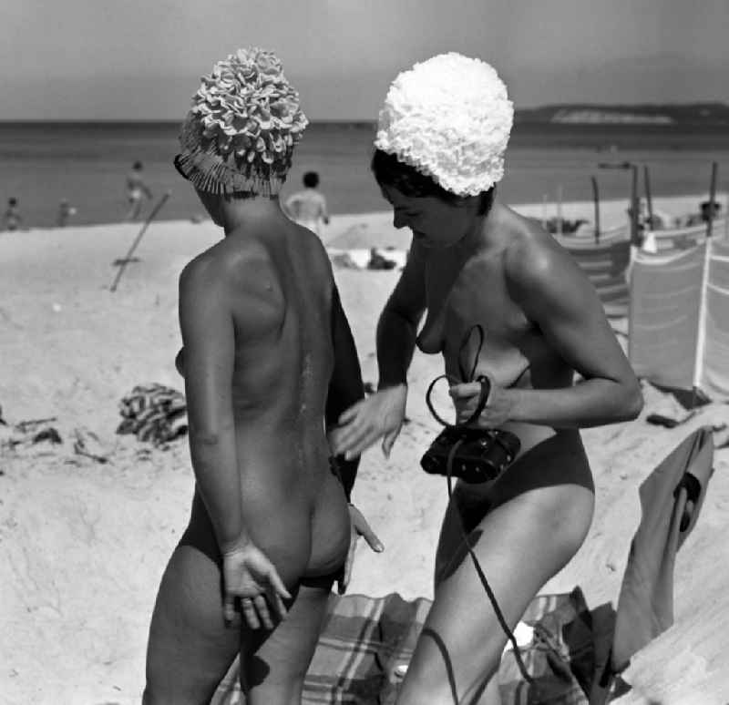 Women apply sunscreen on the nudist beach on the Baltic Sea in the former capital of the GDR, German Democratic Republic
