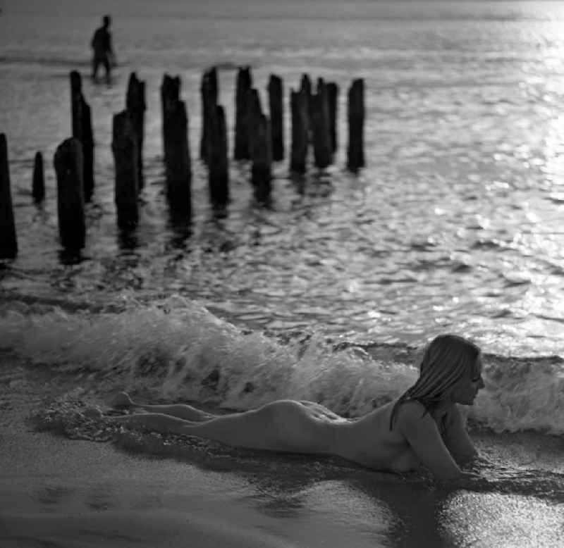 Nude of a young woman at a pier on the Baltic Sea beach in Rostock in the state Mecklenburg-Western Pomerania on the territory of the former GDR, German Democratic Republic
