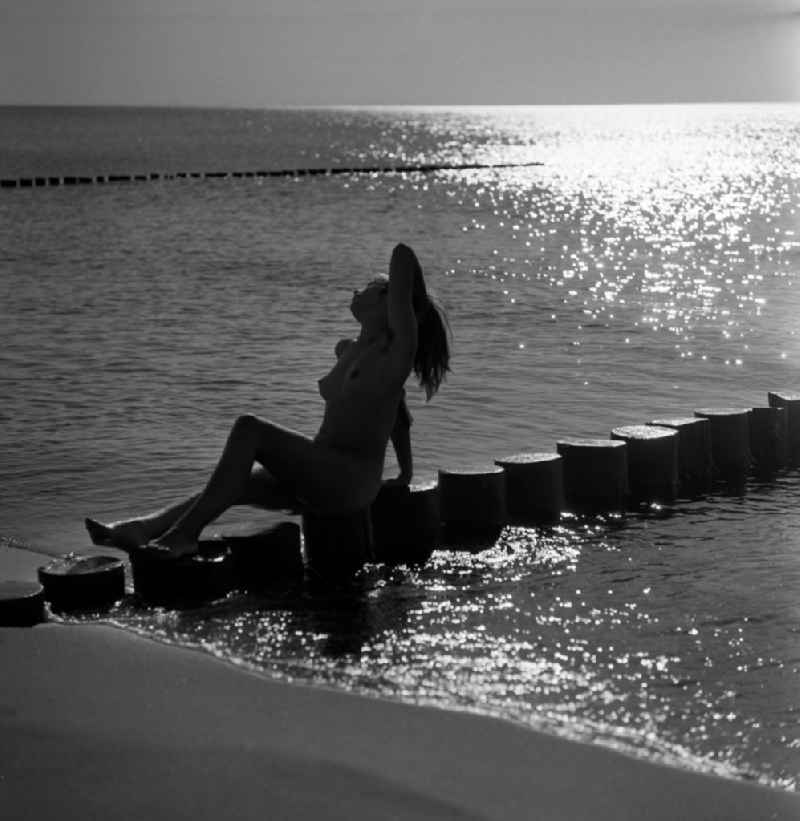 Nude of a young woman at a pier on the Baltic Sea beach in Rostock in the state Mecklenburg-Western Pomerania on the territory of the former GDR, German Democratic Republic