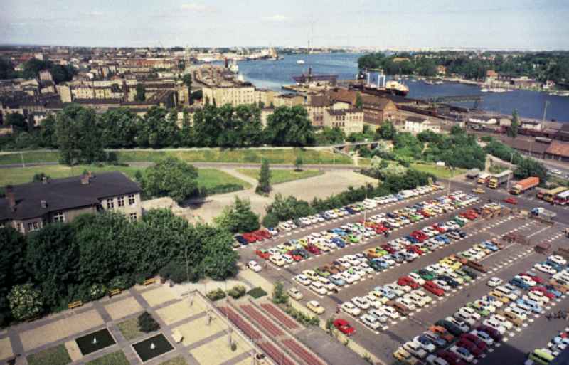 View from the Haus der Schiffahrt over a parking lot with many cars to the riverside Warnowufer at the estuary Unterwarnow in the federal state of Mecklenburg-Western Pomerania in the territory of the former GDR, German Democratic Republic