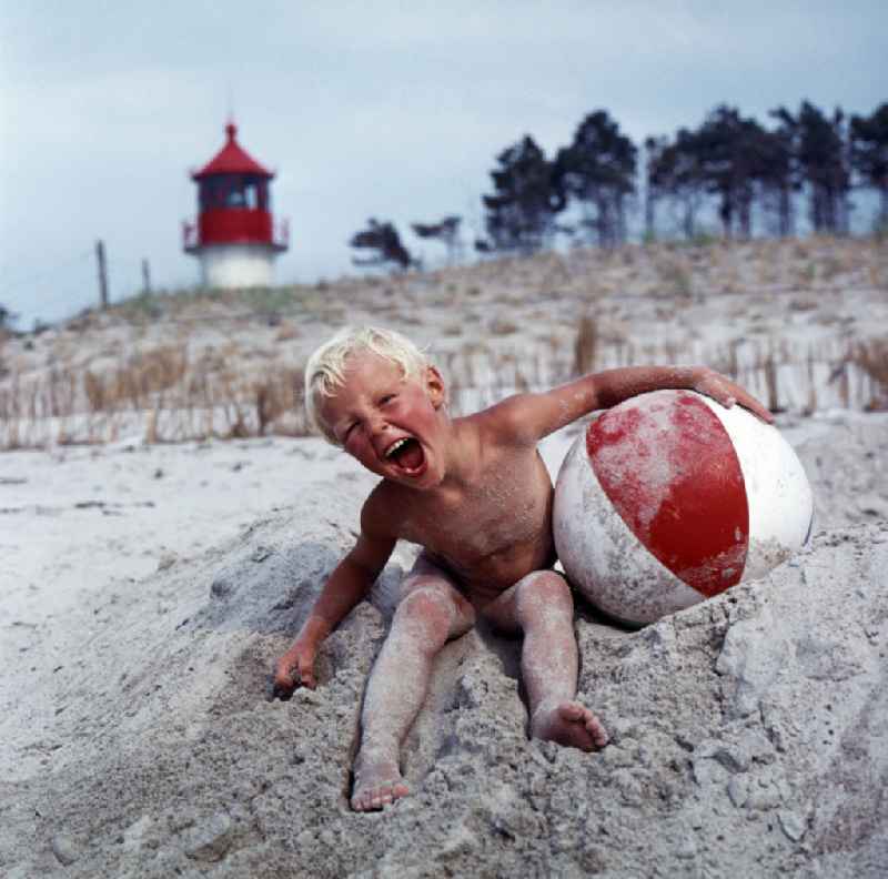 Toddler with red and white beach ball on Warnemuende Beach in Rostock, Mecklenburg-Western Pomerania in the area of the former GDR, German Democratic Republic