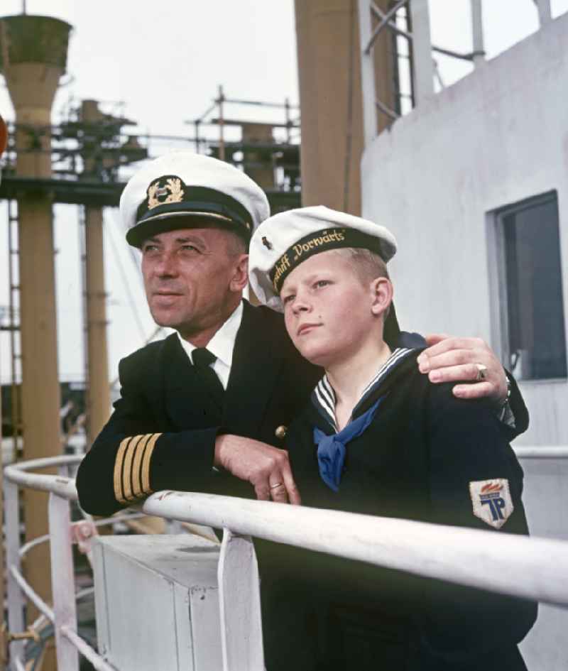 A boy in sailor's uniform and a man in captain's uniform pose on the pioneer ship 'Vorwaerts' in Rostock, Mecklenburg-Vorpommern in the territory of the former GDR, German Democratic Republic