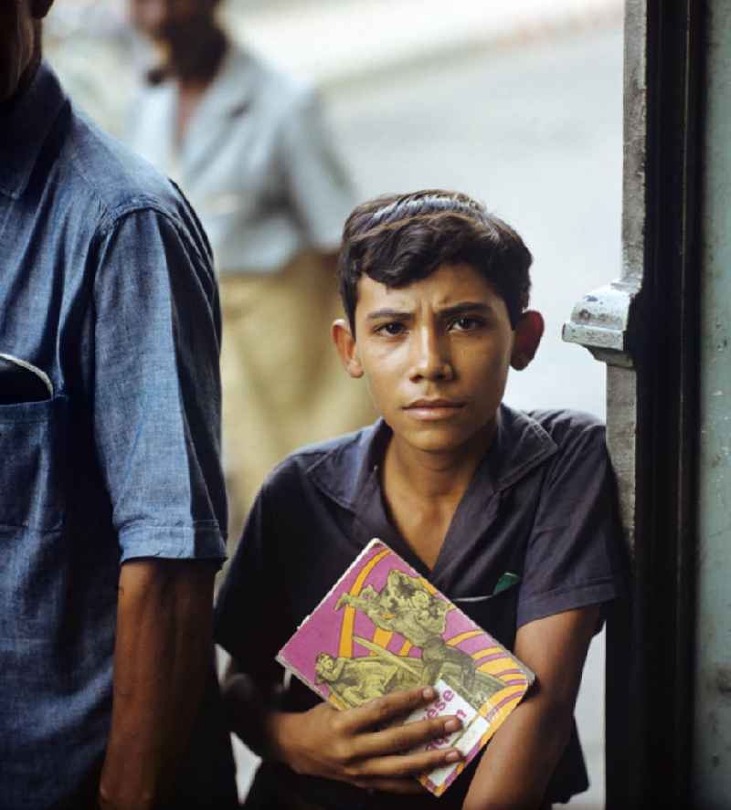 Straßenszene in Santa Clara in Kuba. Porträt, Junge hält ein Buch in der Hand. Portrait,  Street scene in Santa Clara - Cuba. Boy holds a book in his hand.