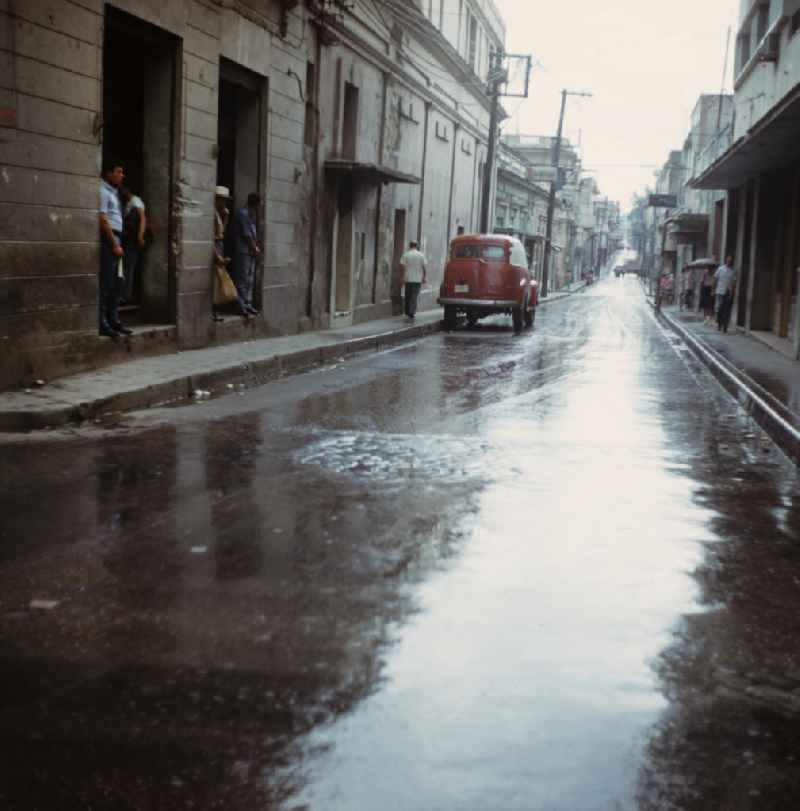 Straßenszene in Santa Clara in Kuba - Passanten suchen in Hauseingängen Unterschlupf vor dem Regen. Street scene in Santa Clara - Cuba.