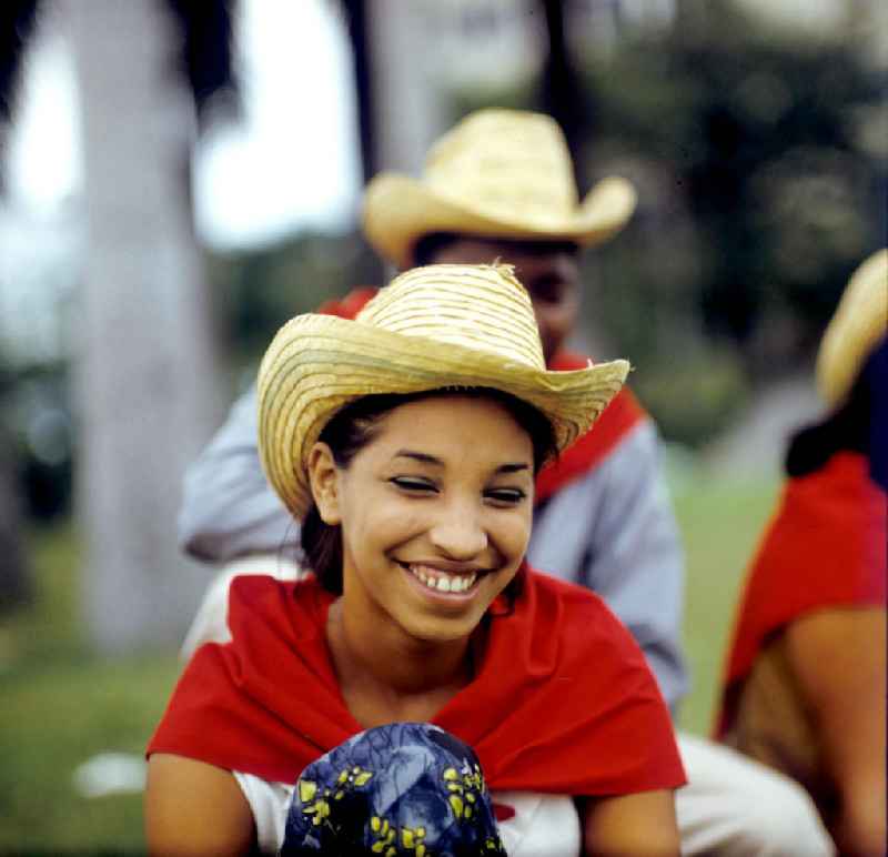 Ein Mädchen mit rotem Halstuch und Strohhut lacht in die Kamera des Fotografen in Santa Clara in Kuba.