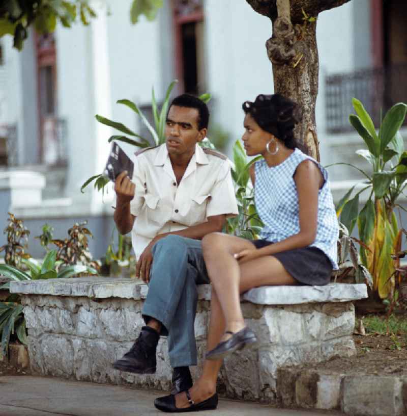 Ein Paar sitzt auf einer Bank im Parque Céspedes in Santiago de Cuba und unterhält sich. A couple in the Céspedes Park.