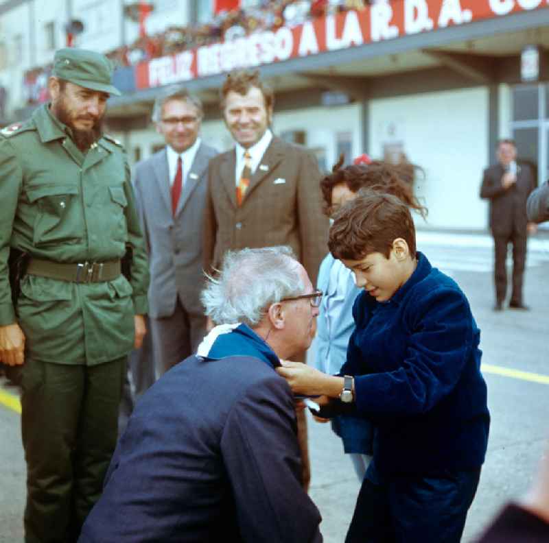 Ein kubanischer Pionier bindet dem Staats- und Parteivorsitzenden der DDR, Erich Honecker, bei dessen Ankunft auf dem Flughafen Santiago de Cuba ein blau-weißes Pionier-Halstuch um. Honecker stattete vom 2