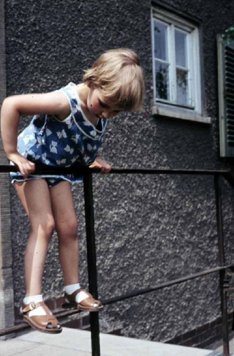 Mädchen klettert am Treppengeländer. Girl climbing on the banister.