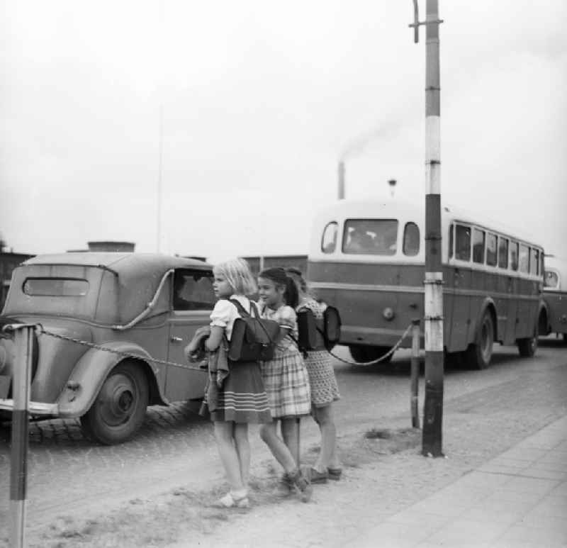 Girls with school bag stand in the street edge and observe the traffic in Schkopau in the federal state Saxony-Anhalt in the area of the former GDR, German democratic republic
